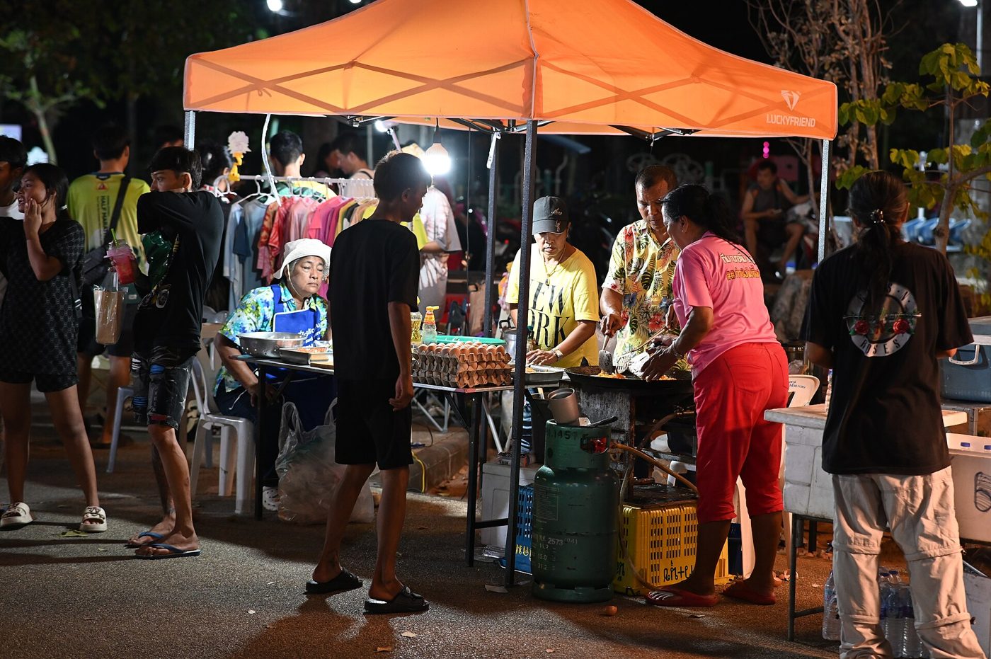Personnes réunies autour d’un stand de nourriture dans un marché nocturne à Sattahip, en Thaïlande.